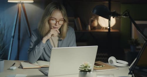 Woman Works on Laptop at Desk at Night