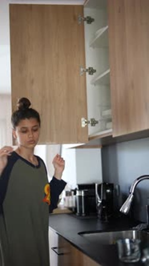 A Person is Organizing Kitchen Cabinets and Loading the Dishwasher During Their Household Chores