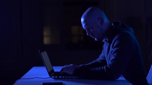 Hacker masculino codificando ataque cibernético em sala escura: conceito de cibercrime