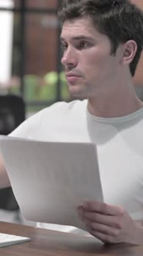 Man Reads Documents at Desk in Modern Office