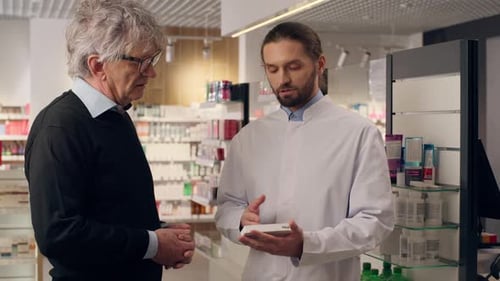 Conseils d'un pharmacien caucasien : médicaments à la clientèle, pilules, vitamines, médicaments, antibiotiques, en pharmacie