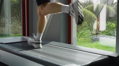 Vista de ángulo bajo de la persona que corre, hace ejercicio cardiovascular en una cinta de correr, gimnasio interior