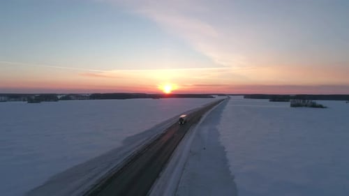 Aerial Wide Shot of Truck Driving on the Intercity Road Among the Fields Covered with Snow on the