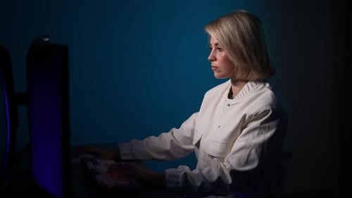 Woman Typing on Computer Keyboard in Dark Room