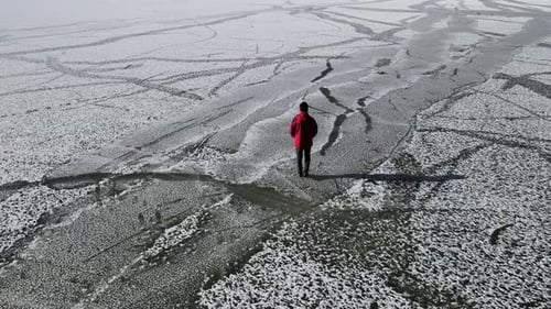 junger Mann geht auf zugefrorenen See