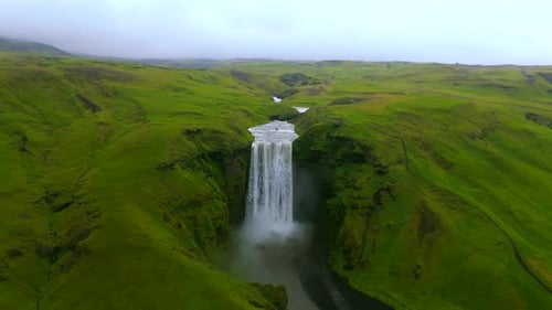 Dramatic Waterfall Flowing Through Lush Green Landscape