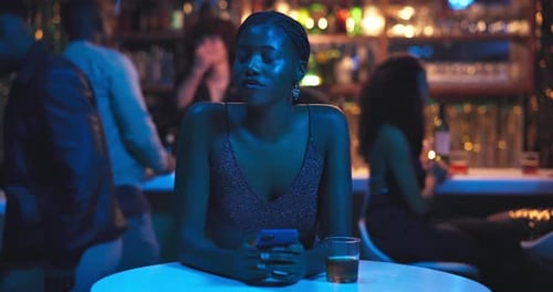 Woman, phone and waiting in night club for date, texting and frustrated thinking with cocktail