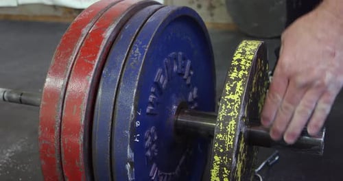 Weightlifter adding plates to deadlift bar.