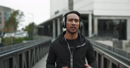 Man Jogging with Headphones Across a Bridge