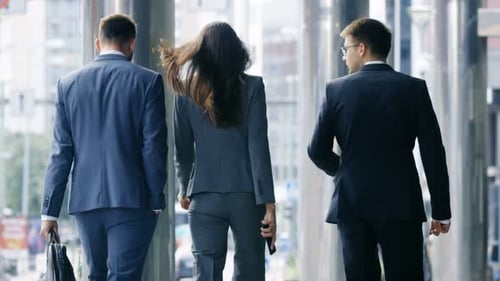 Back View of Three Business People Walking in the Central Business District.