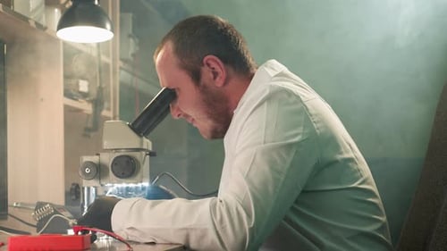 Man Uses Microscope in Laboratory Setting