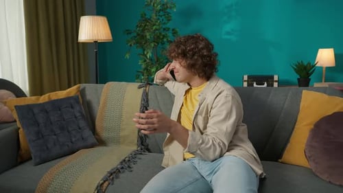Young Adult Talking on Phone, Relaxing on Sofa