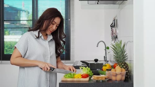 Woman Cutting Vegetables in Bright Kitchen