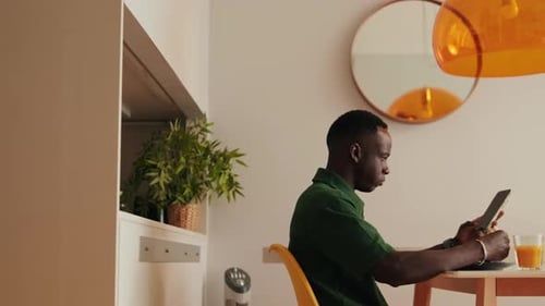 Side view of Young Man Using Tablet at Breakfast