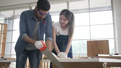 Man and Woman Working Together to Saw Wood