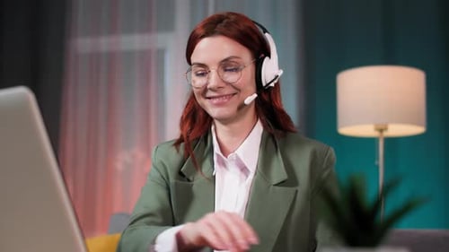 Female Employee in Glasses Works Remotely As a Call Center Operator Communicates with a Client Using