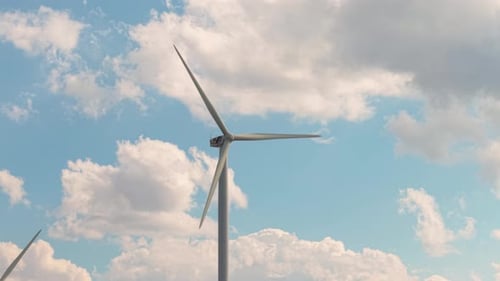 Modern Wind Turbine Head and Blades Spinning Smoothly with Puffy Clouds Behind