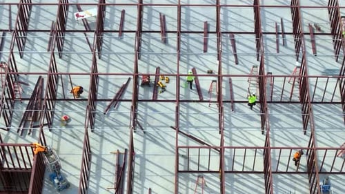 Bauarbeiten an Metallwänden von Büroarbeitern eines Geschäftshauses auf einer großen Baustelle mit