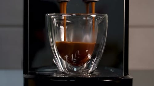 Espresso pouring into double walled glass from machine
