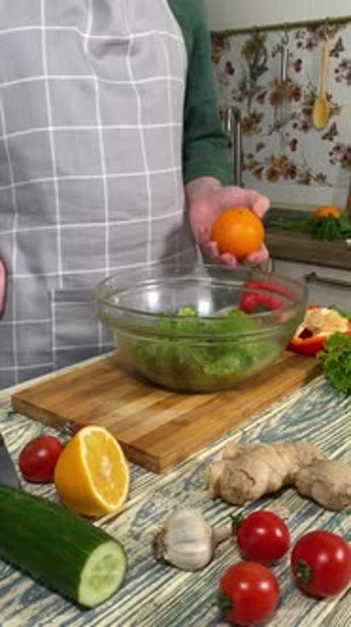 Adult Prepares Orange for Salad in Kitchen