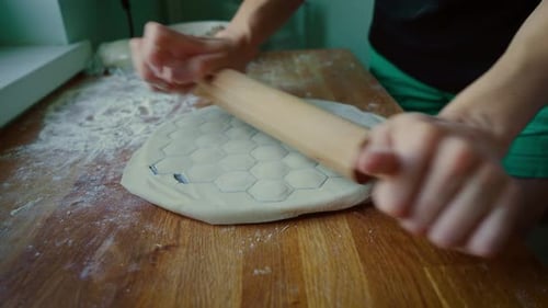 Person Rolling Dough with Pin on Table