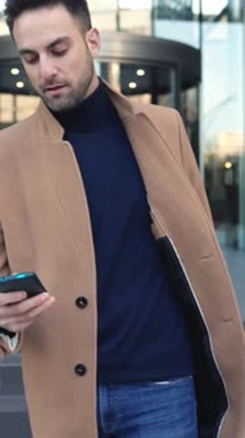 Young Businessman Leaving Office After Work Using Mobile Phone to Make a Call