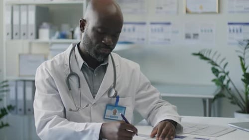 African American Doctor Taking Notes at Desk in Medical Office