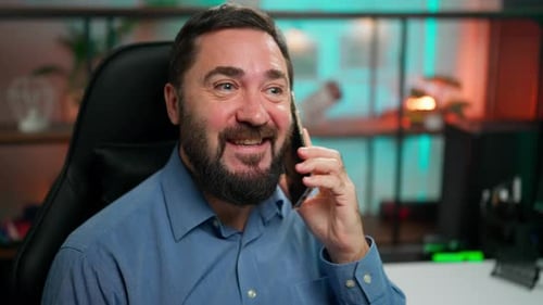 Bearded Man Expressively Talking on Smartphone in Office