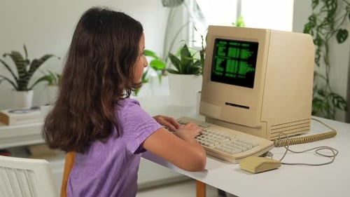 Hispanic Kid Girl Typing or Programming on Retro Old Computer With Source Code Displayed on Monitor.