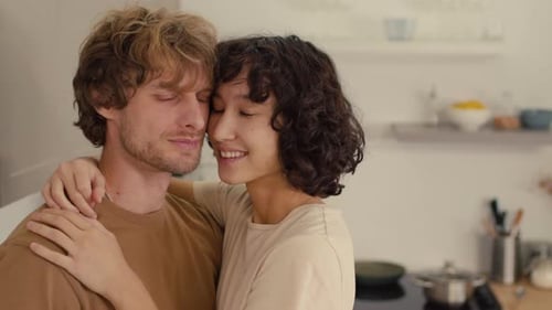 Affectionate Couple Embracing and Smiling in Kitchen