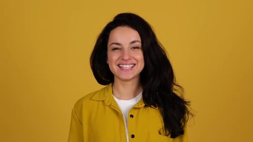 Happy Young Lady Posing in Studio While Throwing Up an Orange and Showing It at Camera Isolated on