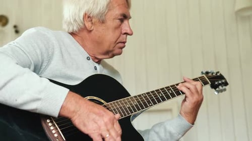 Mature Man Plays Acoustic Guitar in Home