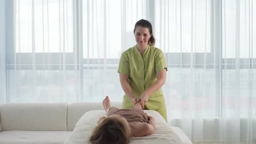 Woman Massaging a Child's Legs at Home