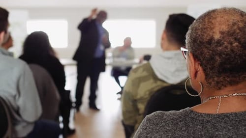 Audience Listening To Community Leader Talking At Town Hall Meeting