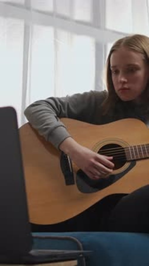 Teen Girl Practicing Acoustic Guitar at Home While Following Online Lesson on Laptop Relaxing on