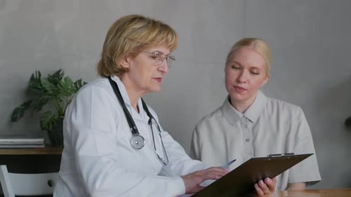Doctor Reviews Medical Chart with Patient in Clinic