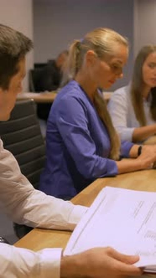 Vertical of Three Colleagues Working Late at Night in Office with Laptop and Documents