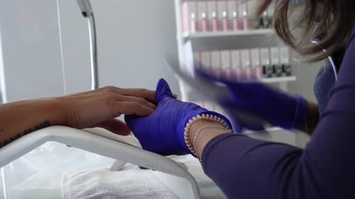 The manicurist polishes the nails with a nail file