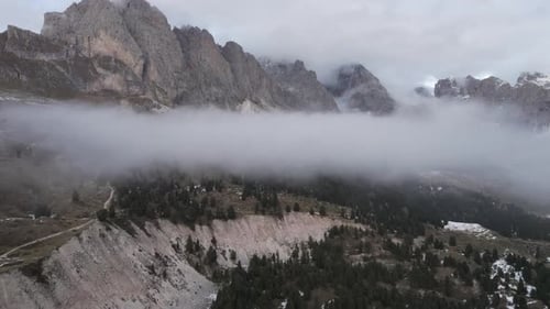 Areal shot of the beautiful Italian Alps, mountain peeks covered in clouds