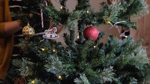 Woman Decorating Christmas Tree with Colorful Ornaments
