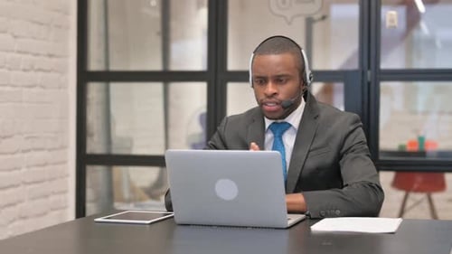 Young Adult Teleworking on Laptop with Headset