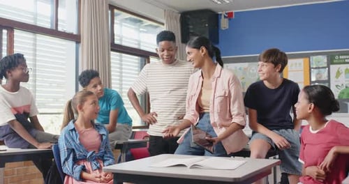 In school, teacher using tablet and interacting with students in classroom