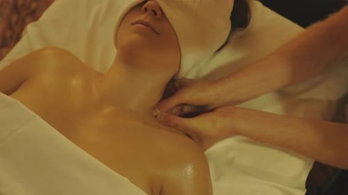 Ein Masseur massiert den Schulterbereich einer Frau im Spa-Salon