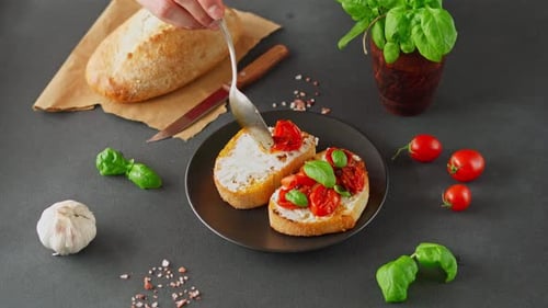 Man's hand puts grilled tomatoes on Bruschetta with Ricotto Cheese