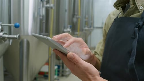 Kaukasischer Braumeister arbeitet an einer Tablette in einer Bierfermentationsanlage