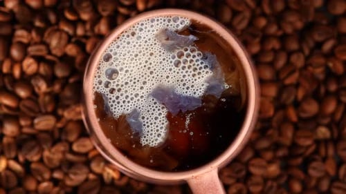 Tasse Kaffee mit Milch auf Kaffeebohnen-Hintergrund von oben