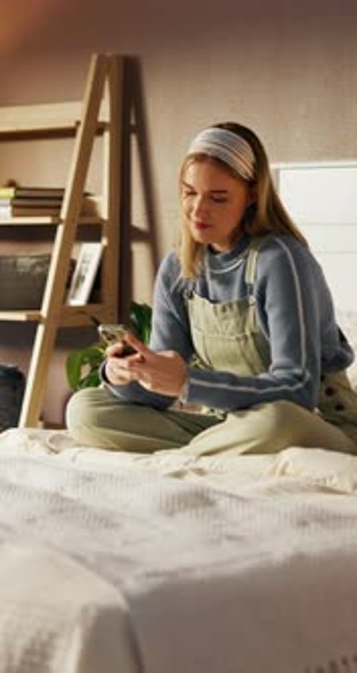 Woman Sits on Bed Using Mobile Phone