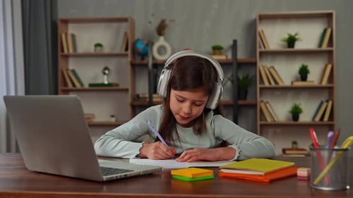 Young Child Girl Studying at Home Small Girl Sits at Desk and Attends School Class Online on Laptop