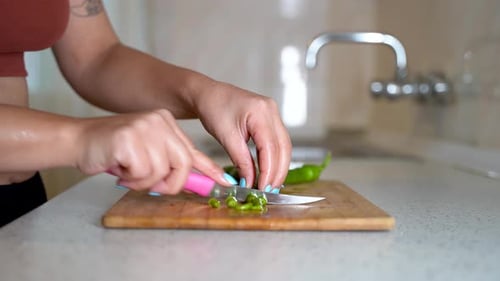 Young woman cutting green chili pepper 4K