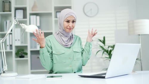 Sad young muslim woman read bad news on laptop computer sitting at workplace in office. Frustrated s